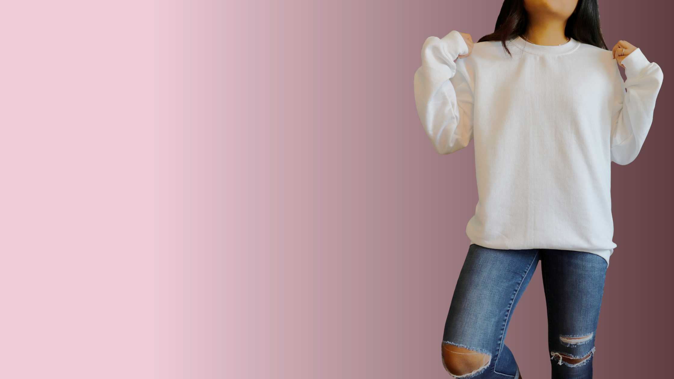 Person wearing a white sweater and ripped jeans on a pink background